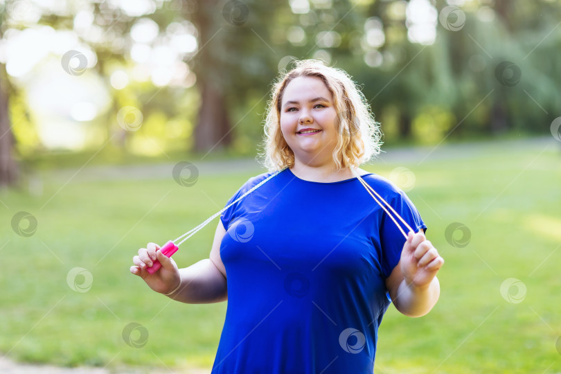 Скачать Блондинка больших размеров со скакалкой в руках позирует в парке. Концепция здорового образа жизни. фотосток Ozero