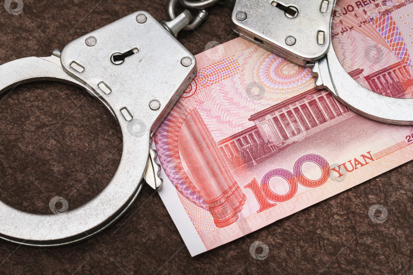 Скачать Сто юаней и наручники на столе. Понятие незаконных валютных операций фотосток Ozero