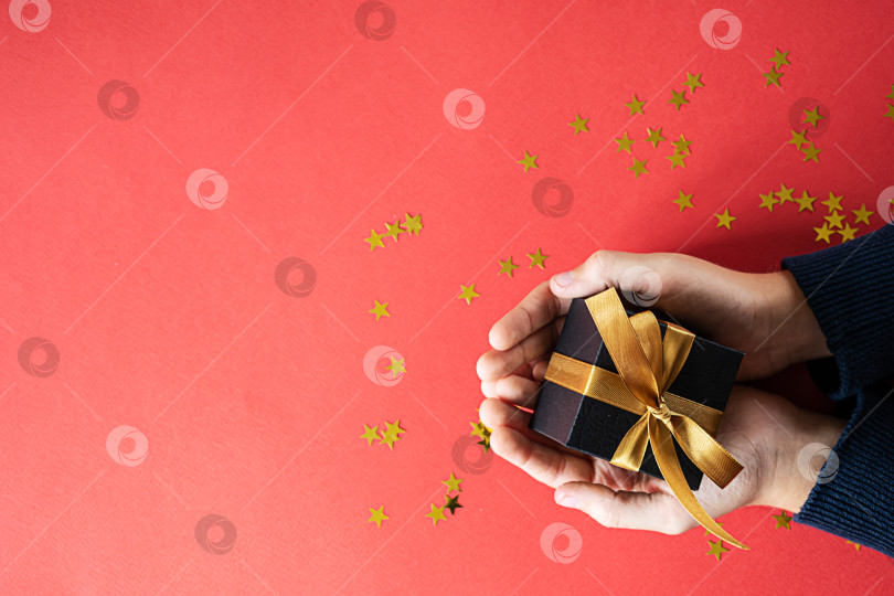 Скачать руки, держащие подарочную коробку на красном фоне фотосток Ozero