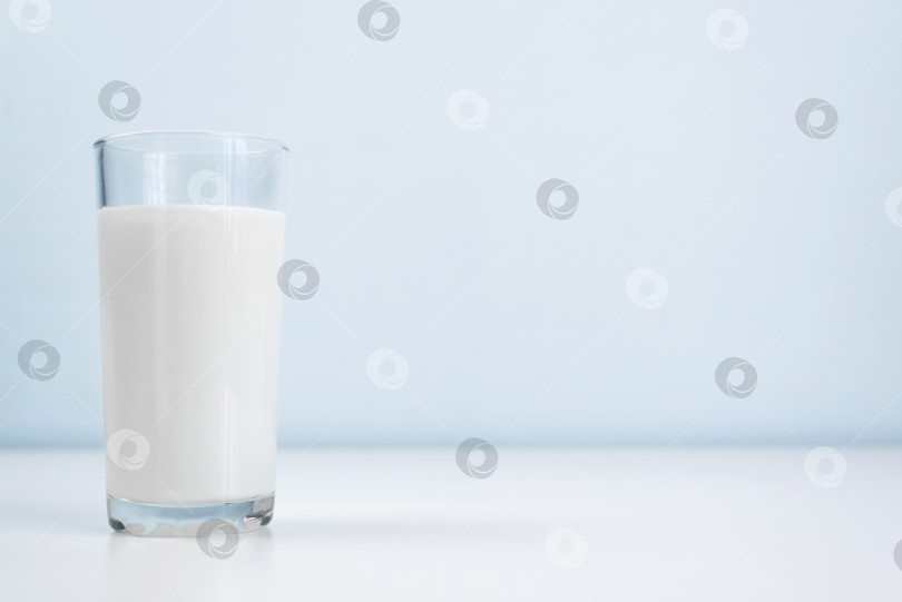 Скачать Стакан молока стоит на белом столе в помещении. Минималистичная фотография, пространство для копирования. Здоровое питание, концепция диеты фотосток Ozero