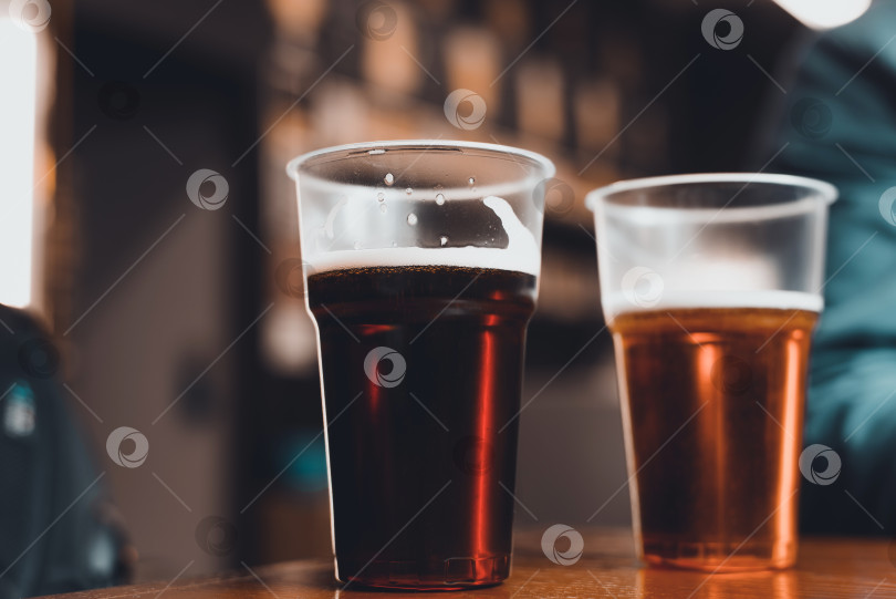 Скачать Два бокала темного и светлого пива на столе в пабе, крупным планом. Выборочный фокус, размытие фотосток Ozero