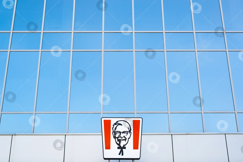 Скачать Логотип ресторана быстрого питания KFC снаружи на фоне витрины торгового центра. Полковник Сандерс. Смоленск, Россия 24.03.2021 фотосток Ozero