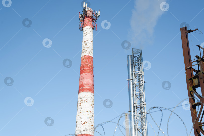 Скачать Башня с трубой. Поднимающийся дым в ясное светло-голубое небо. Концепция загрязнения окружающей среды. фотосток Ozero
