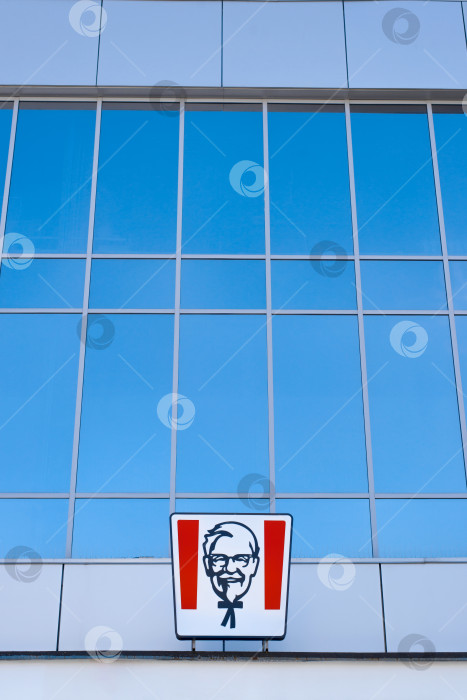 Скачать Логотип ресторана быстрого питания KFC снаружи на фоне стеклянной витрины. Вертикальная фотография. Смоленск, Россия 24.03.2021 фотосток Ozero