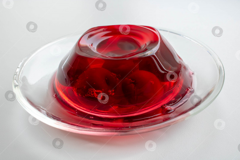 Скачать Стеклянная тарелка с ягодами вишни в красном желе на белом фоне. фотосток Ozero