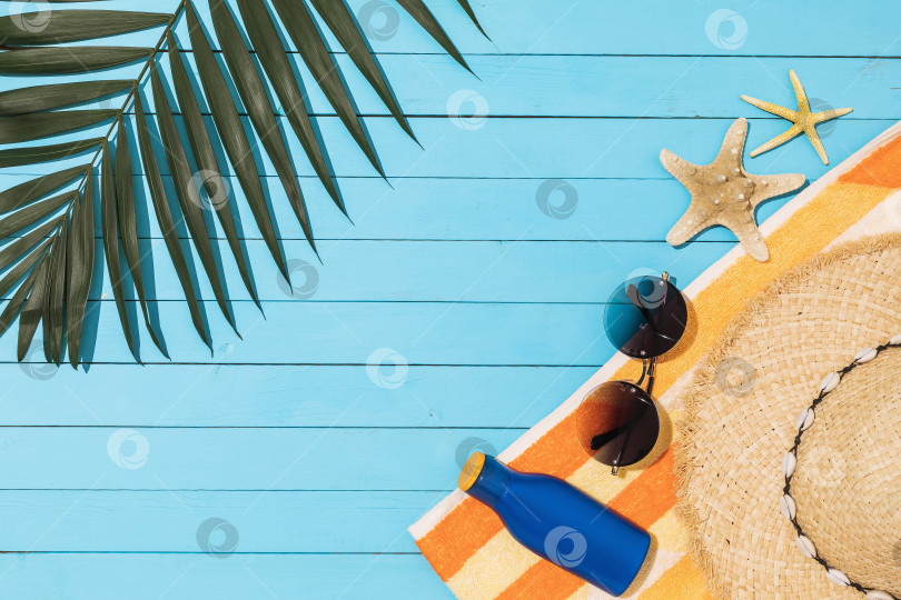 Скачать Крем для загара, шляпа, солнцезащитные очки и пальмовый лист на деревянном синем фоне с пробелом для копирования фотосток Ozero