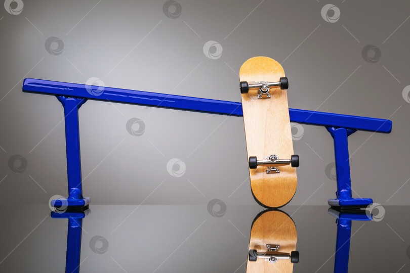 Скачать Деревянный гриф и синие металлические перила для катания на маленьких скейтбордах на сером градиентном фоне фотосток Ozero