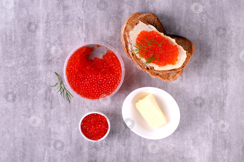 Скачать Бутерброд с красной икрой и сливочным маслом на сером столе. фотосток Ozero