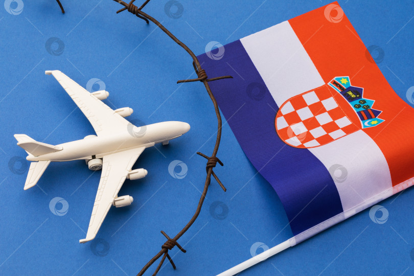 Скачать Игрушечный самолет, флаг Хорватии и колючая проволока на синем фоне, концепция нарушения воздушной границы Хорватии фотосток Ozero