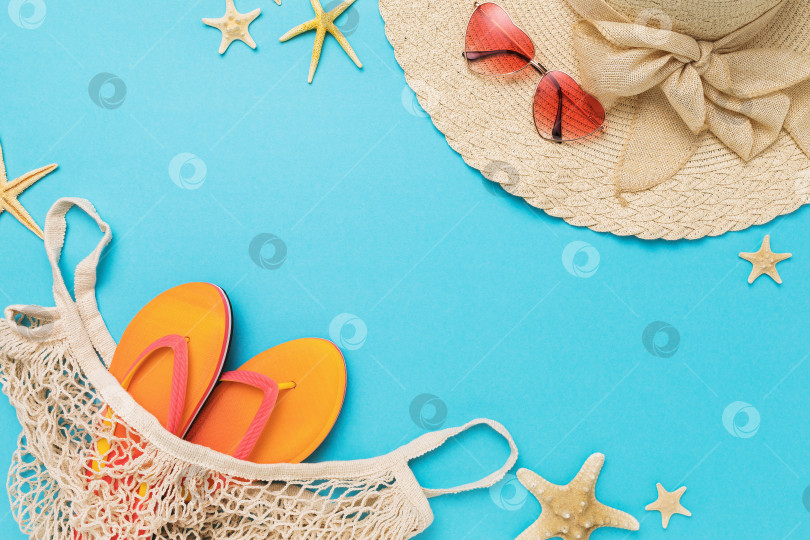 Скачать Шляпа, солнцезащитные очки, пляжные тапочки в сумке и морские звезды на синем фоне с пробелом для текста фотосток Ozero