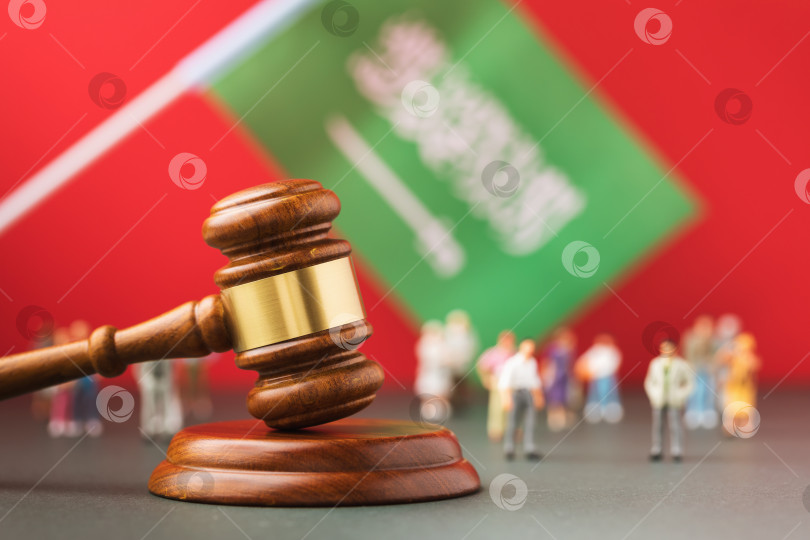 Скачать Судейский молоток, флаг и пластмассовые игрушечные человечки на красном фоне, концепция судебного разбирательства в Саудовской Аравии фотосток Ozero