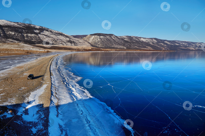 Скачать Замерзшее озеро Байкал. Вид на прозрачный лед в солнечный январский день. Зимнее путешествие по России фотосток Ozero