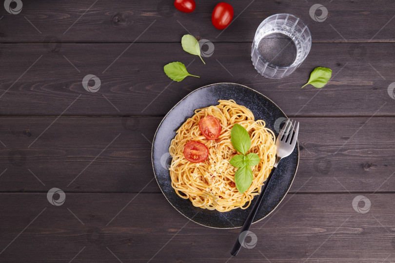 Скачать Макароны-спагетти с помидорами, соусом, базиликом на фоне темного дерева. фотосток Ozero