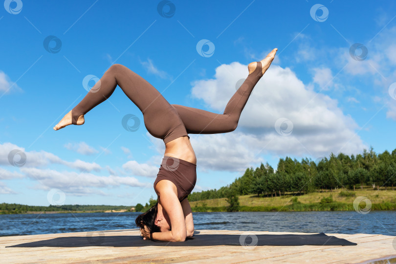 Скачать Женщина, практикующая йогу, выполняет вариацию ширшасаны фотосток Ozero