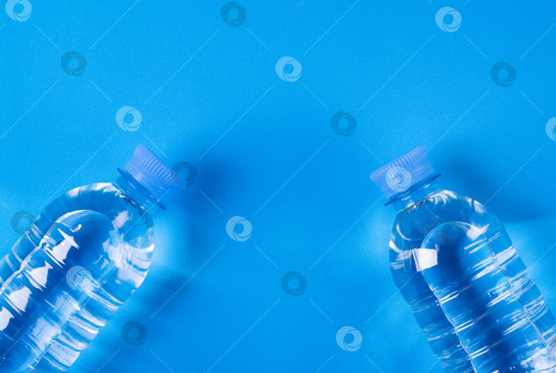 Скачать Две бутылки чистой питьевой воды на синем фоне с пробелом для копирования. Монохромный. Вид сверху. фотосток Ozero