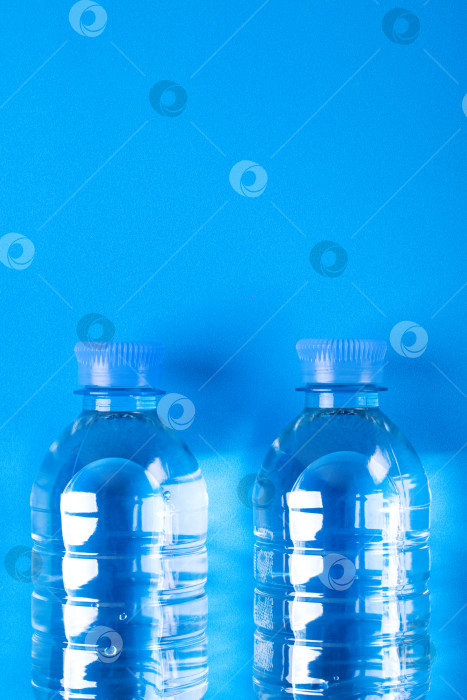 Скачать Две бутылки чистой питьевой воды на синем фоне. Монохромный. Вид сверху. фотосток Ozero