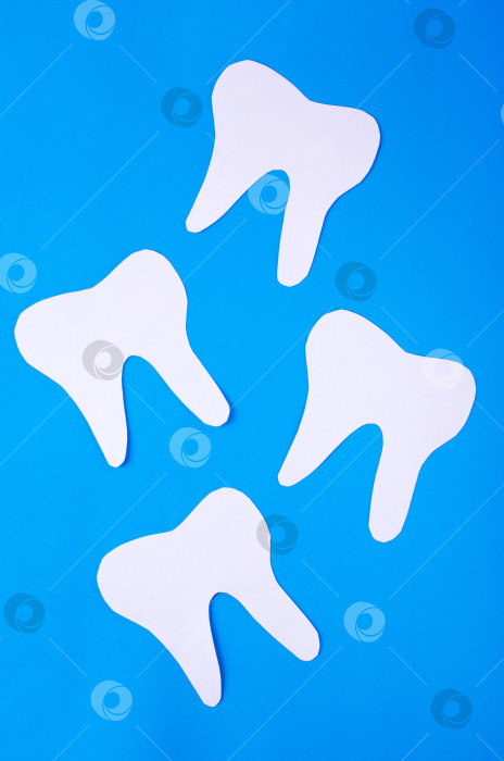Скачать Плоская накладка с бумажными зубьями на синем фоне. Символ стоматолога и гигиены полости рта. фотосток Ozero