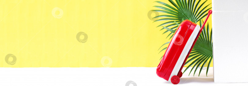 Скачать Веб-баннер с красным чемоданом и пальмовыми листьями на желтом фоне. Концепция путешествий и летних каникул. фотосток Ozero
