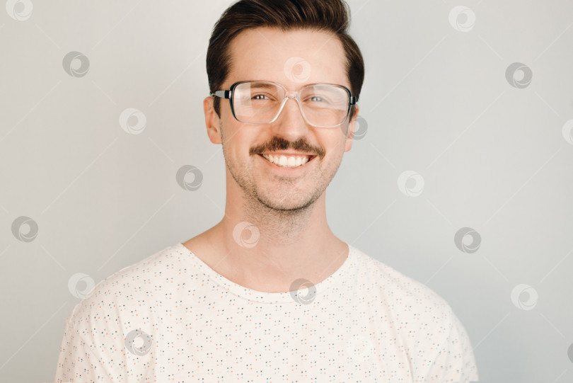 Скачать Молодой улыбающийся мужчина в больших очках и модной футболке в помещении. Портрет Хипсетра фотосток Ozero
