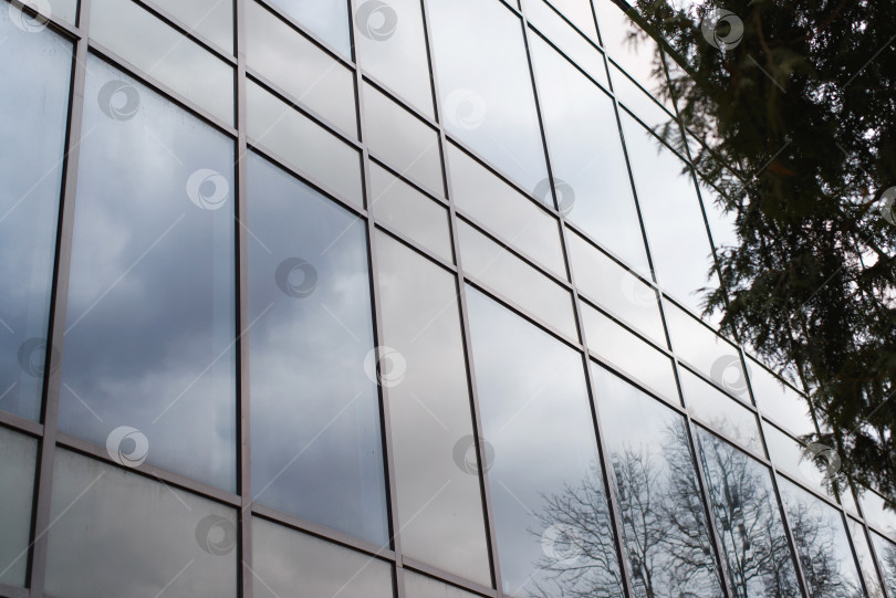 Скачать Фасад стеклянного здания снаружи в пасмурный день, крупный план. Отражение неба в очках. фотосток Ozero