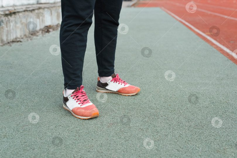 Скачать Женские ноги в кроссовках стоят на резиновом полу стадиона, снаружи. Концепция тренировок, спорта фотосток Ozero