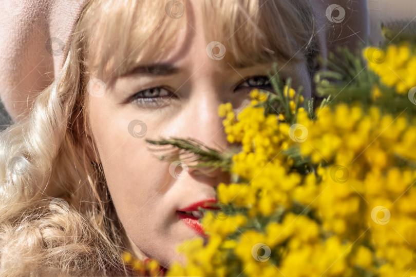 Скачать Молодая женщина стоит с букетом желтой мимозы и нюхает цветы в парке. Концепция весеннего праздника - 8 марта, Пасха, Женский день фотосток Ozero