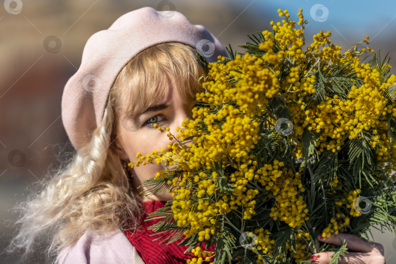 Скачать Молодая женщина стоит с букетом желтой мимозы и нюхает цветы в парке. Концепция весеннего праздника - 8 марта, Пасха, Женский день фотосток Ozero