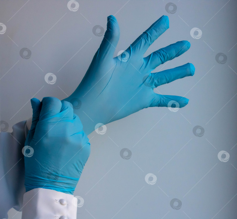 Скачать Научный эксперимент - подросток в белом лабораторном халате и синих медицинских перчатках делает игрушку из слизи на выставке технологий - крупный план руки подростка. Образовательная и развлекательная концепция. фотосток Ozero