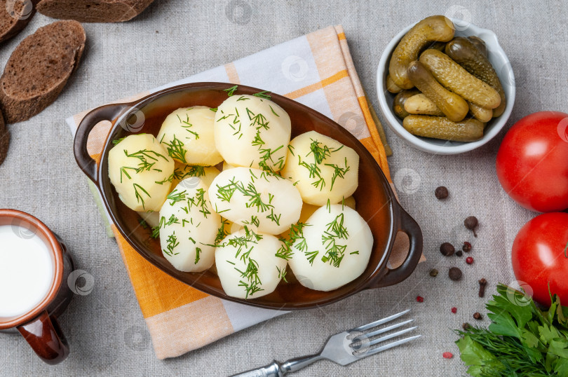 Скачать Отварной картофель с зеленью в глиняном горшочке. Рядом в белой чашке фотосток Ozero