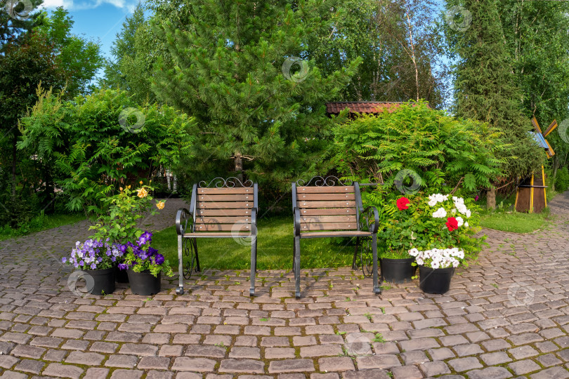 Скачать Два кованых кресла в летнем саду с каменной кладкой из бе фотосток Ozero