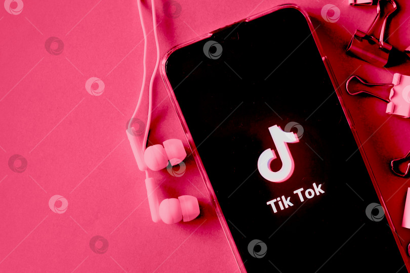 Скачать Тверь, Россия - 9 апреля 2020 года, логотип tik tok на экране смартфона с наушниками. Значок Тик-Ток. логотип текущего приложения. Социальная сеть Tiktok. Демонстрация цветов 2023 года - Viva Magenta фотосток Ozero