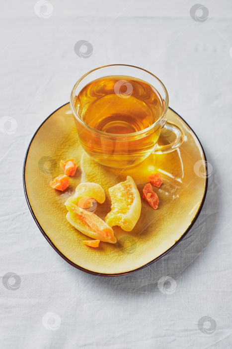 Скачать Вкусный черный чай в стеклянной чашке и цукаты на желтом блюдце фотосток Ozero