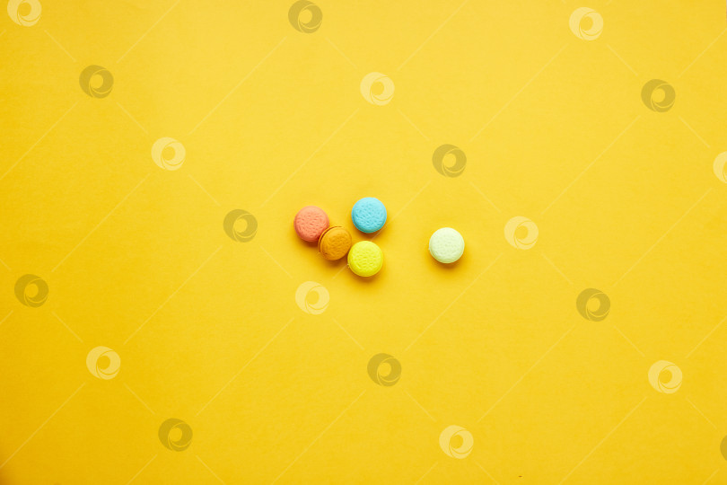 Скачать Разноцветные пирожные с макарунами на желтом фоне. фотосток Ozero