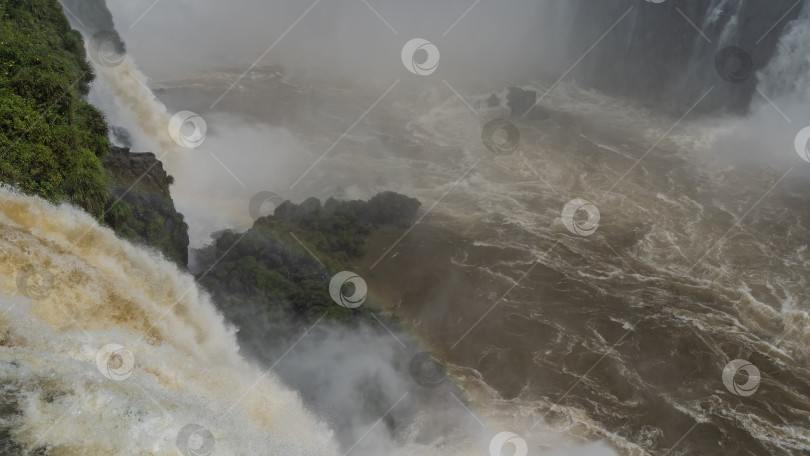 Скачать Мощный поток воды, обрушивающийся в бушующую реку. фотосток Ozero
