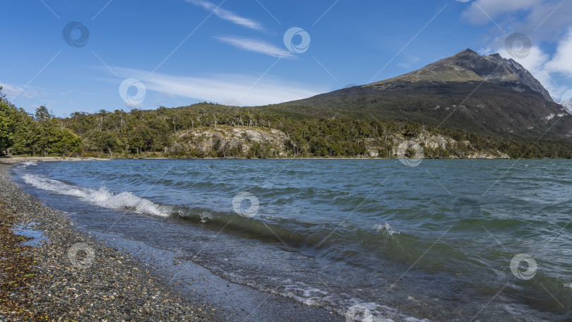 Скачать Волны изумрудного озера набегают пеной на галечный пляж. фотосток Ozero
