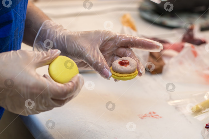 Скачать кондитер собирает половинки печенья macarons. крупный план. концепция домашней пекарни. фотосток Ozero