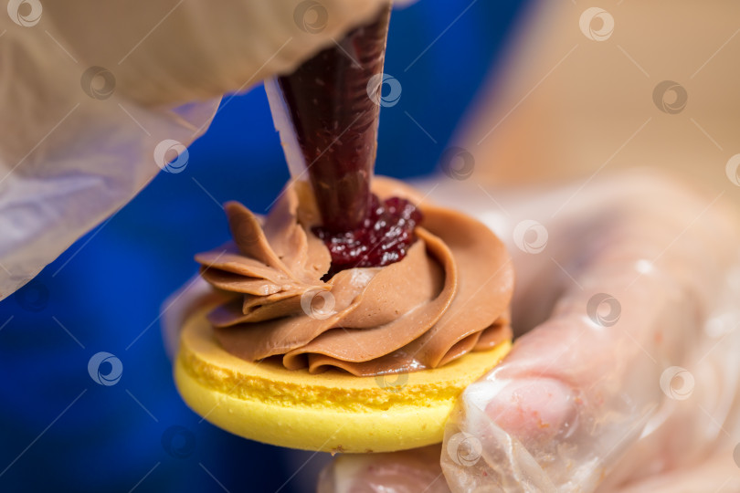 Скачать шеф-кондитер выдавливает начинку на печенье macarons. крупный план. концепция домашней пекарни. фотосток Ozero