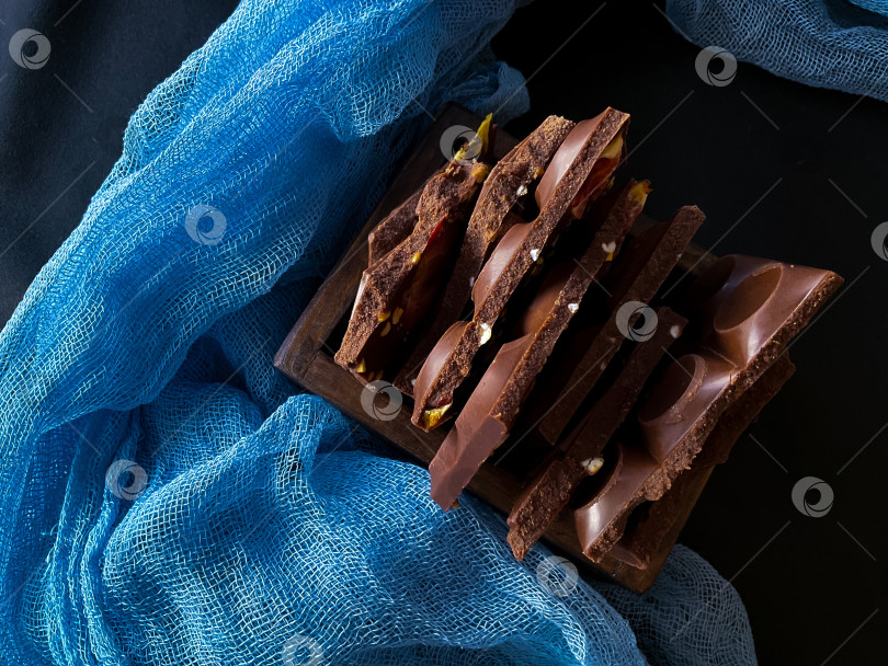 Скачать Кусочки шоколада с орехами и изюмом на темном фоне фотосток Ozero