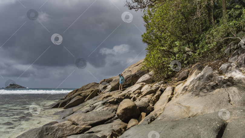 Скачать Мужчина стоит на скалистом склоне прибрежного холма, глядя вдаль. фотосток Ozero
