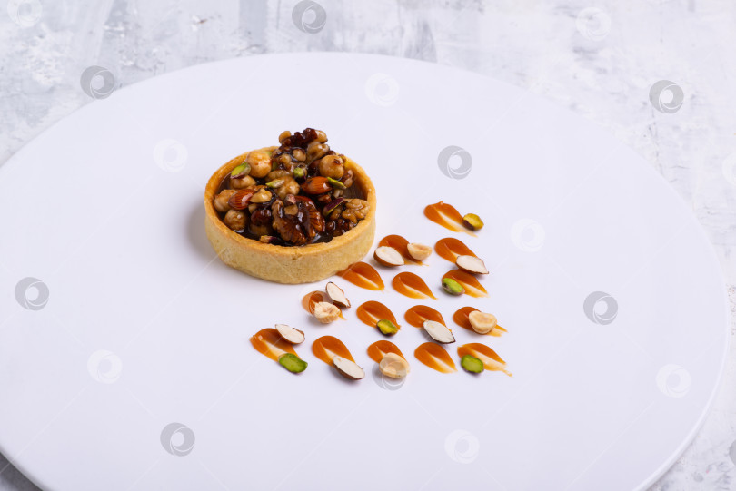 Скачать Аппетитные тарталетки с начинкой из фундука грецких орехов покрытые слоем жидкой карамели фотосток Ozero