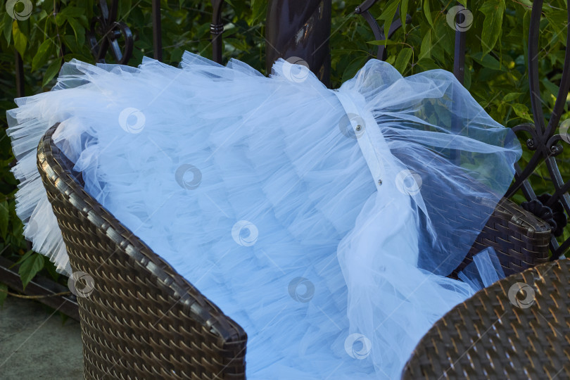 Скачать Белое платье с вуалью на коричневом стуле из искусственного ротанга. фотосток Ozero