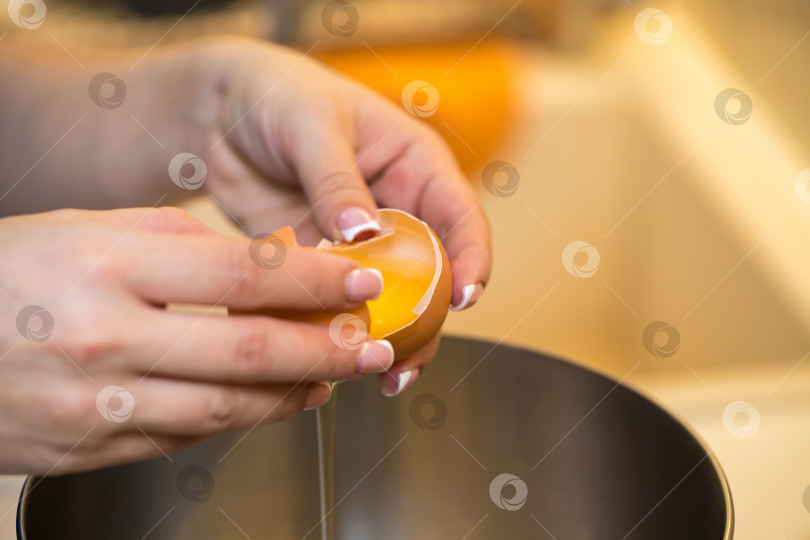 Скачать женщина отделяет белок от желтка разбитого куриного яйца. руки крупным планом. концепция домашней пекарни. фотосток Ozero