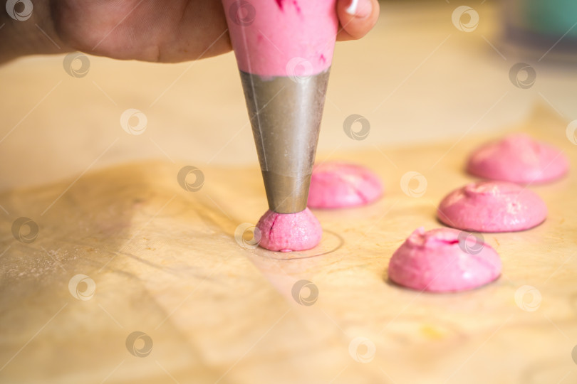 Скачать кондитер выдавливает капли розового теста для макарон. крупный план. концепция домашней пекарни. фотосток Ozero