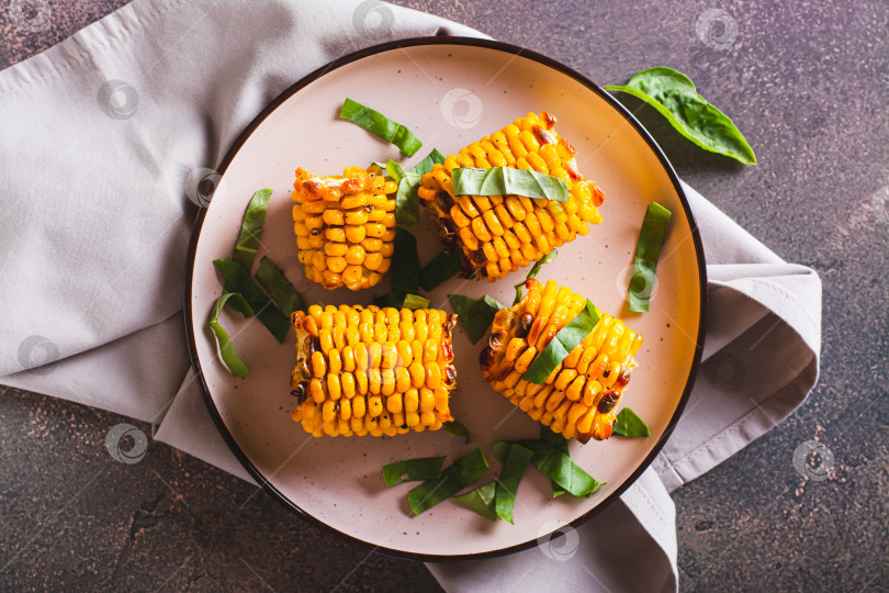 Скачать Крупный план запеченных початков сладкой кукурузы со сливочным маслом, чесноком и зеленью фотосток Ozero