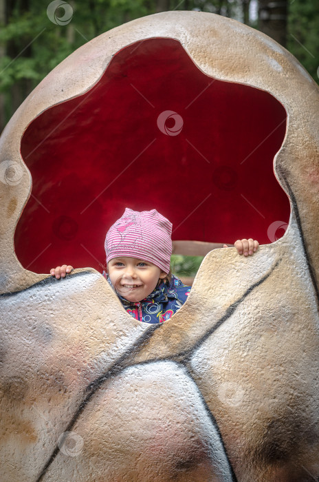 Скачать Ульяновск, Россия - 08 мая 2023 года: Девушка прячется в имитации яйца динозавра в парке Победы. фотосток Ozero
