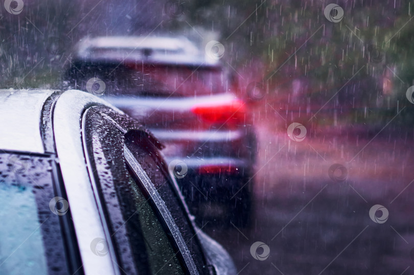Скачать Сильный дождь падает на крышу автомобиля во время грозы. Красный стоп-сигнал в темноте. фотосток Ozero