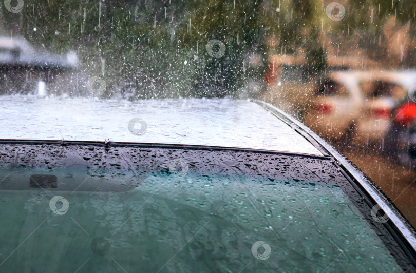Скачать Сильный летний дождь с градом. Сильные потоки воды падают на крышу спортивного автомобиля. фотосток Ozero