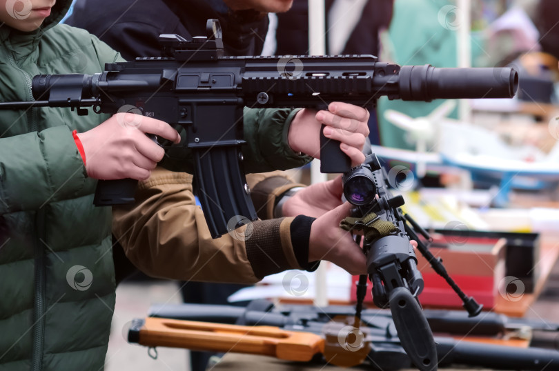 Скачать Штурмовая винтовка в руках подростка на выставке оружия. фотосток Ozero