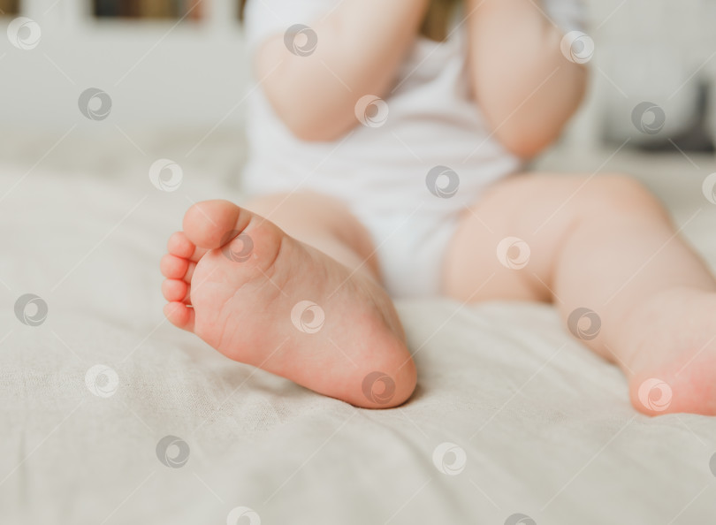 Скачать мамины руки удерживают ножки ребенка на хлопчатобумажной подстилке, гигиена и уход за новорожденным. фотосток Ozero