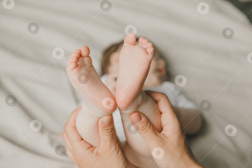 Скачать мамины руки удерживают ножки ребенка на хлопчатобумажной подстилке, гигиена и уход за новорожденным. фотосток Ozero